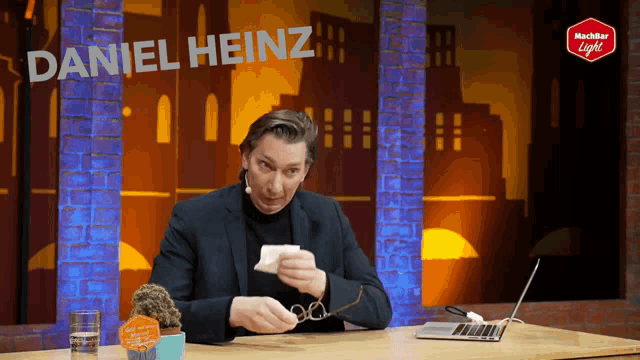 a man sitting at a table with the name daniel heinz written on the top