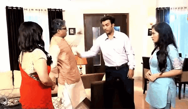 a group of people are standing in a living room and one of them is holding another man 's arm