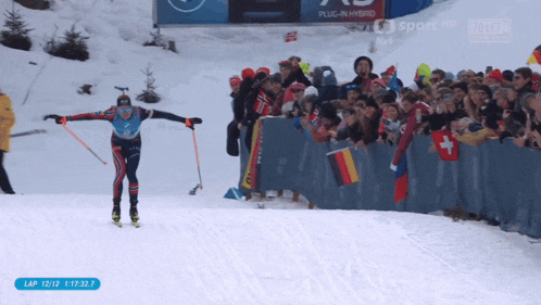 a skier crosses the finish line in front of a crowd with a sign that says plug-in hybrid