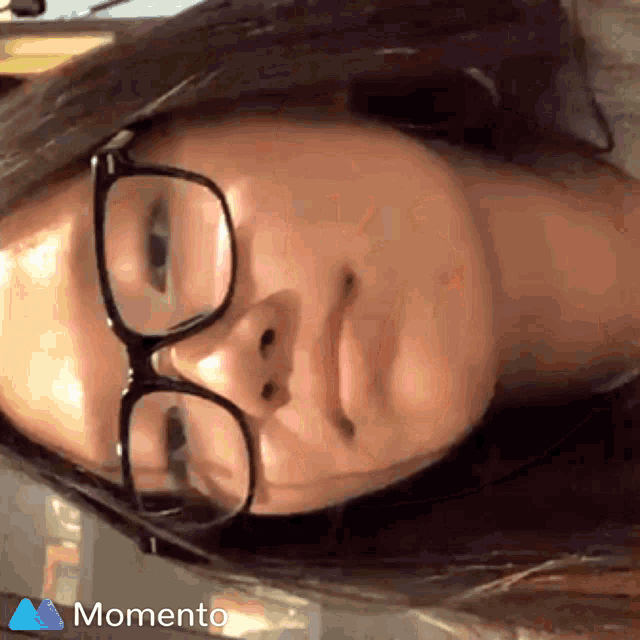 a woman wearing glasses has a momento logo on her face