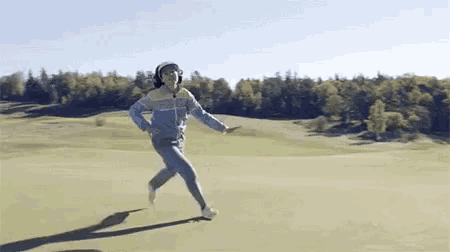 a man is running on a golf course with his arms outstretched .