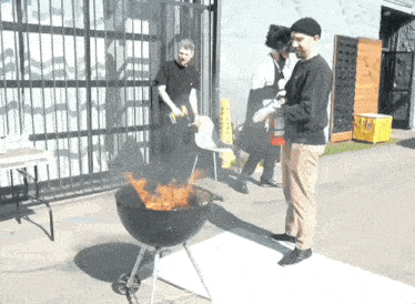 a man is standing next to a barbecue grill with a fire extinguisher in front of him