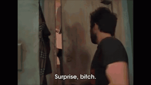 a man with a beard is standing in a doorway and saying surprise bitch .