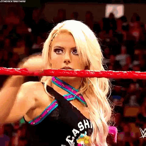 a woman is standing in a wrestling ring with a red rope .