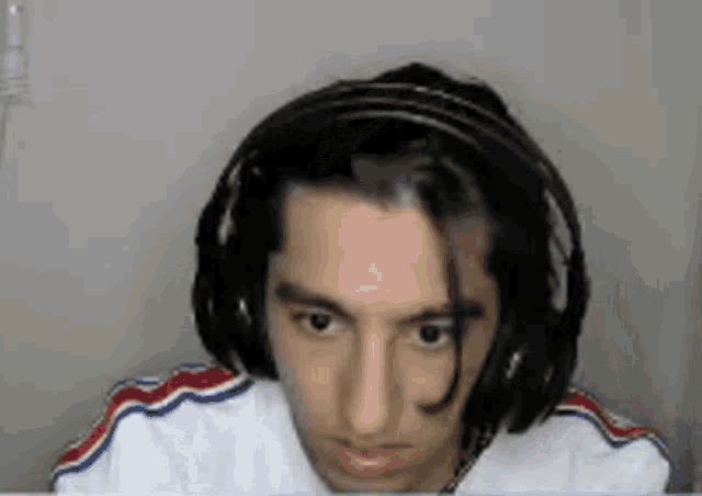 a young man wearing headphones and a white shirt is looking at a computer screen .