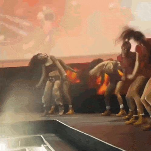 a group of women are dancing on a stage with a red background