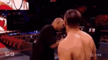 a man without a shirt is standing next to another man in a ring .