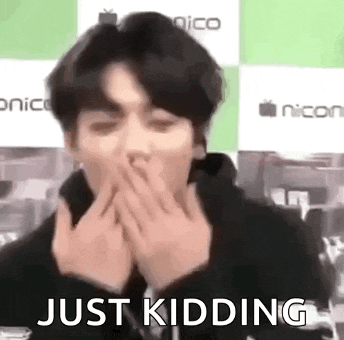 a man is covering his mouth with his hands and the words `` just kidding '' are written next to him .