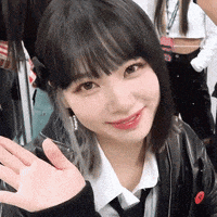 a close up of a woman wearing a black jacket and tie waving her hand
