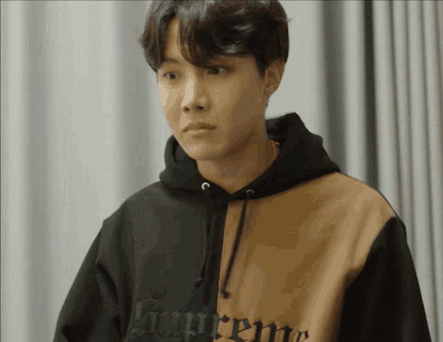 a young man wearing a black and brown supreme sweatshirt