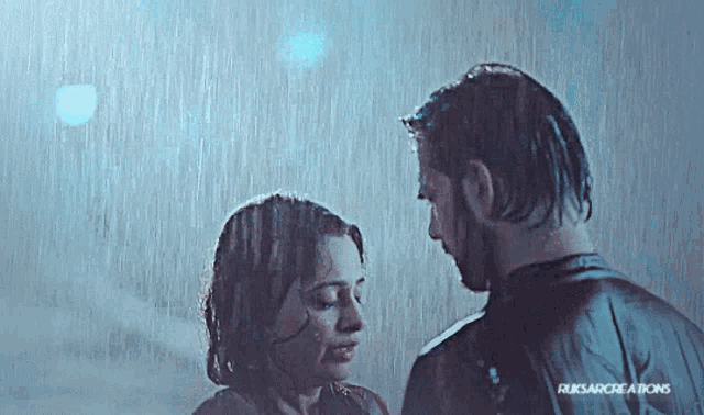 a man and woman are kissing in the rain .