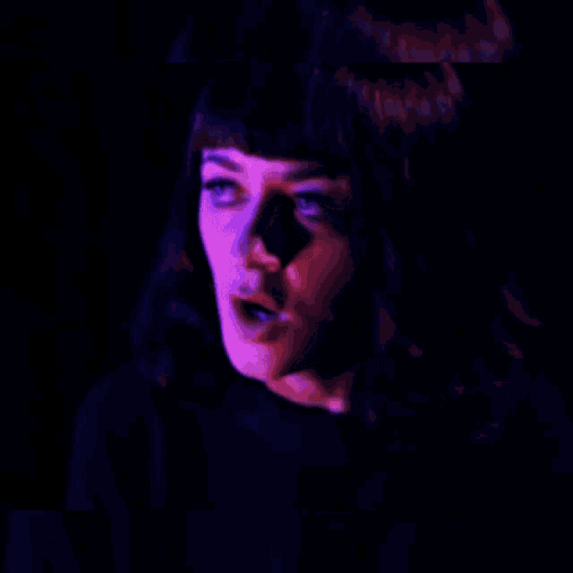 a close up of a woman 's face with a purple light behind her