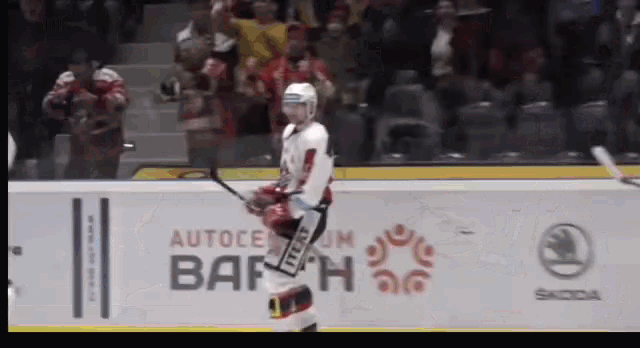 a hockey player stands on the ice in front of an ad for autocentrum bahn