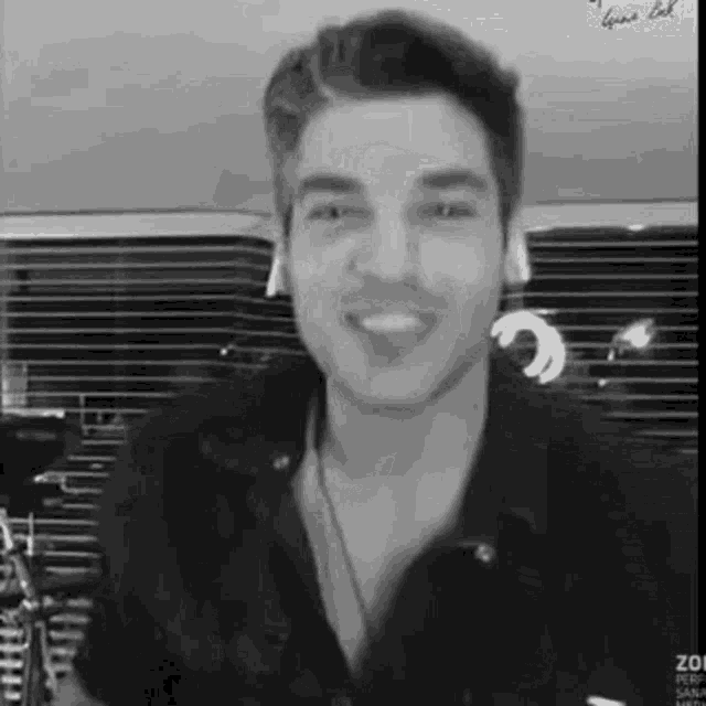 a black and white photo of a man wearing headphones smiling .