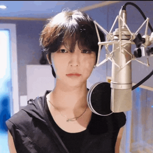 a young man is standing in front of a microphone in a recording studio .