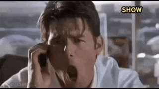 tom cruise is yawning while talking on a cell phone .