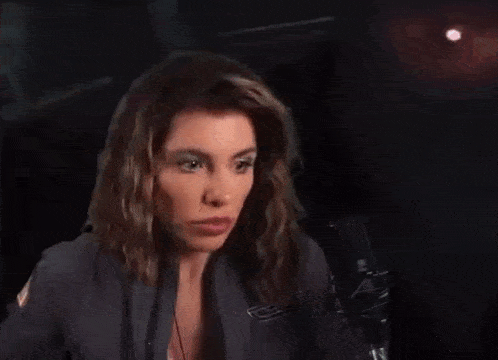 a woman is yawning while sitting in front of a microphone in a dark room .