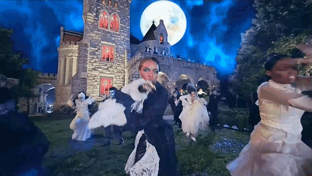 a group of people dancing in front of a castle at night