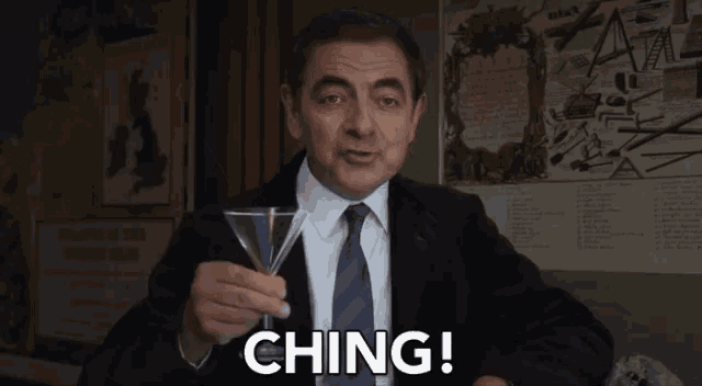 a man in a suit and tie is holding a martini glass and saying ching