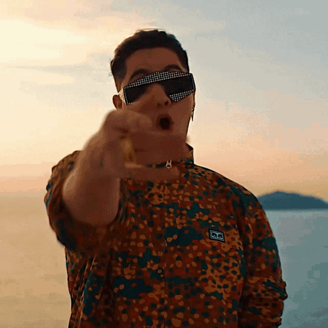 a man wearing sunglasses and a shirt with the letter h on the front