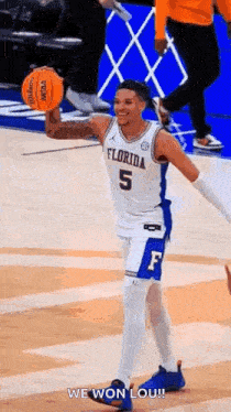 a basketball player is holding a basketball in his hand on a court and smiling .