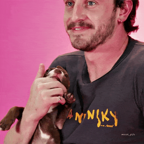 a man holding a small dog wearing a shirt that says aninky