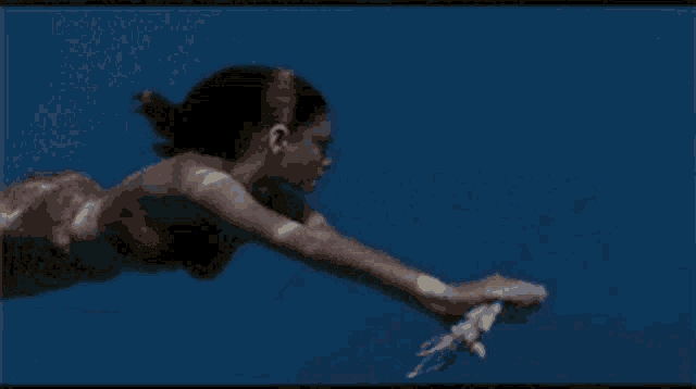 a woman in a bikini is swimming underwater in a blue ocean .