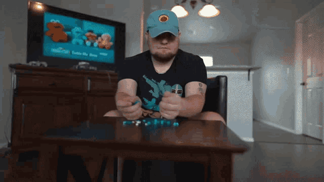 a man sitting at a table with a sesame street tv on the wall behind him
