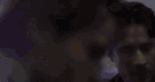 a close up of a person 's face with a purple background behind them