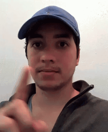 a man wearing a blue hat and a black jacket is making a funny face