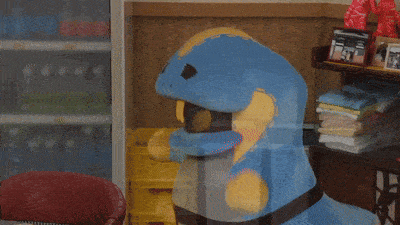 a stuffed animal in a blue and yellow outfit is sitting on a table