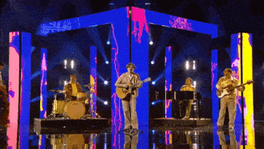 a man singing into a microphone in front of a band