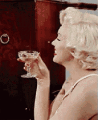 a woman is holding a glass of wine and smoking a cigarette .