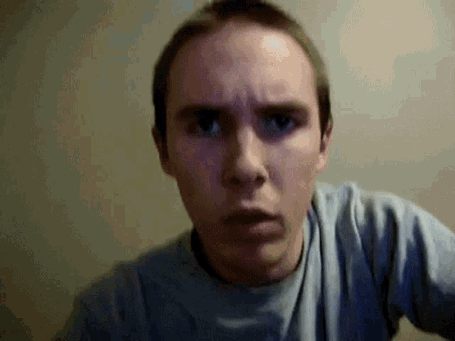 a man in a blue shirt is making a surprised face .