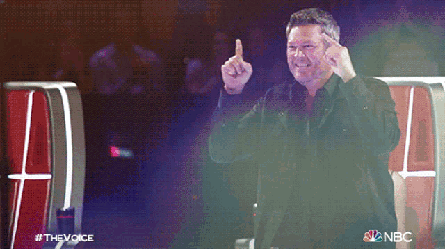 a man giving the middle finger in front of a sign that says the voice