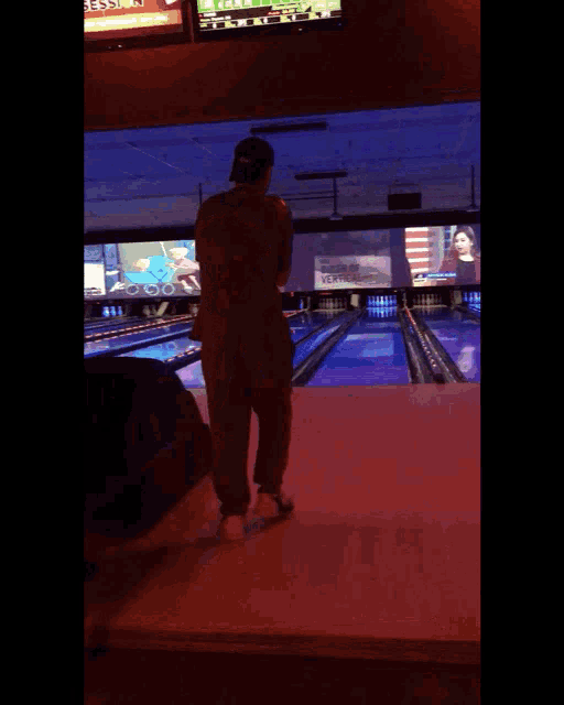 a man standing in a bowling alley with a tv screen behind him that says ' fox ' on it