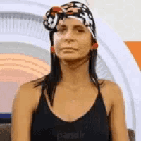 a woman wearing a black tank top and a bandana on her head is making a funny face .