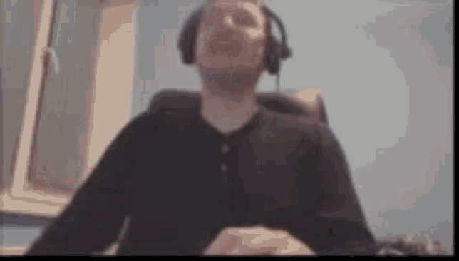 a man wearing headphones is sitting at a desk in front of a computer screen .