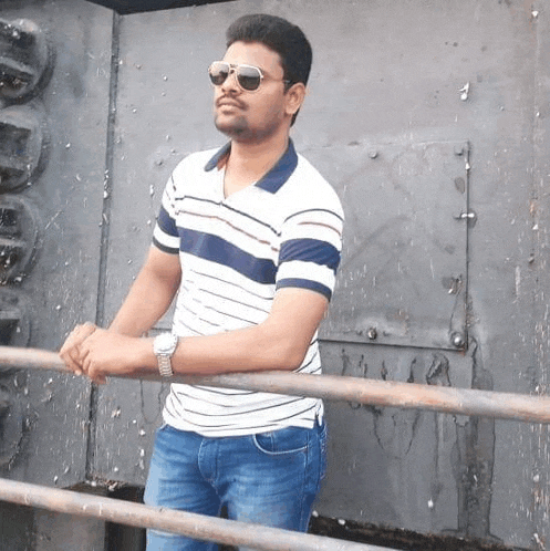 a man wearing sunglasses is leaning on a railing .