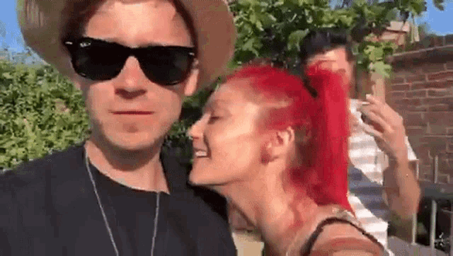 a man and a woman with red hair are standing next to each other .