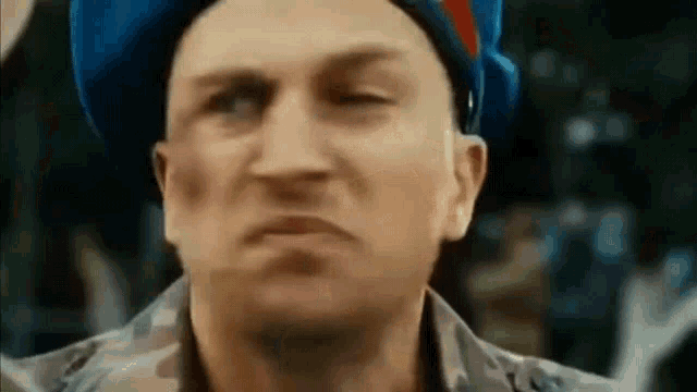a close up of a man wearing a blue hat making a face .