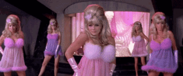 a woman in a pink and purple dress is surrounded by other women in pink and purple dresses .