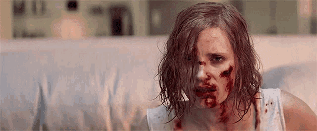 a woman with blood on her face is sitting on a couch