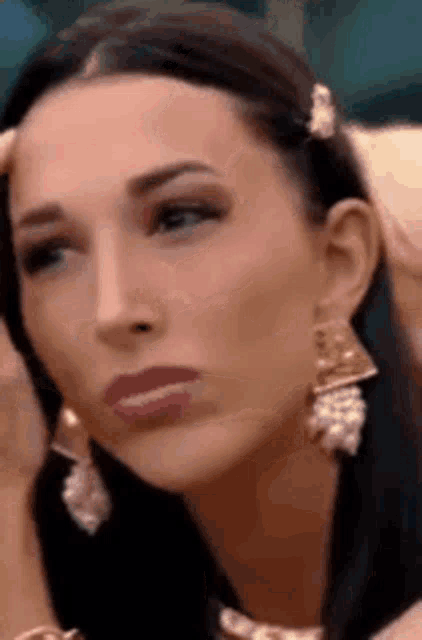 a close up of a woman wearing earrings making a face .