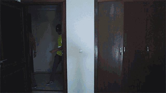 a man wearing sunglasses and a yellow shirt stands in a dark room