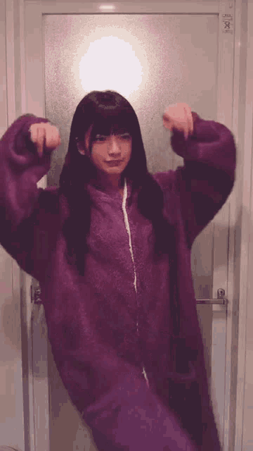 a woman in a purple sweater is standing in front of a door with the number x on it