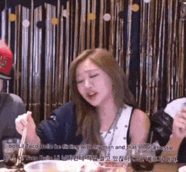 a woman is sitting at a table eating food with chopsticks and a caption that says no lil taco belle