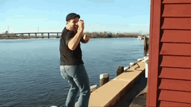 a man is standing on a dock near a river