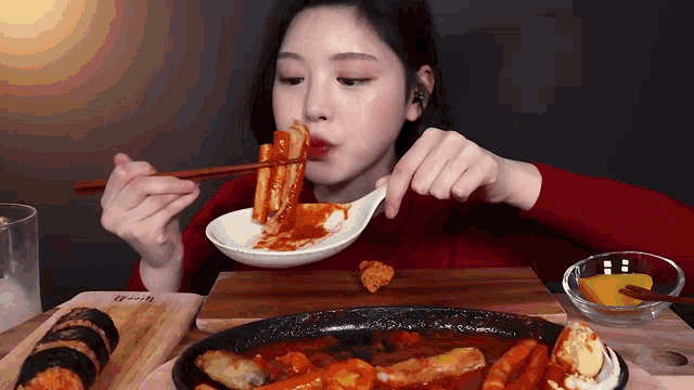 a woman is eating a meal with chopsticks and a spoon