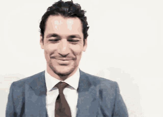 a man in a suit and tie is smiling with his eyes closed .